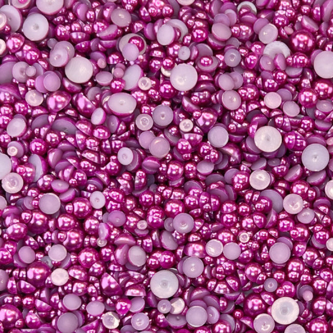A close-up view of flat-back acrylic pearls in various sizes, predominantly in pink and purple hues, used for crafting and embellishments.